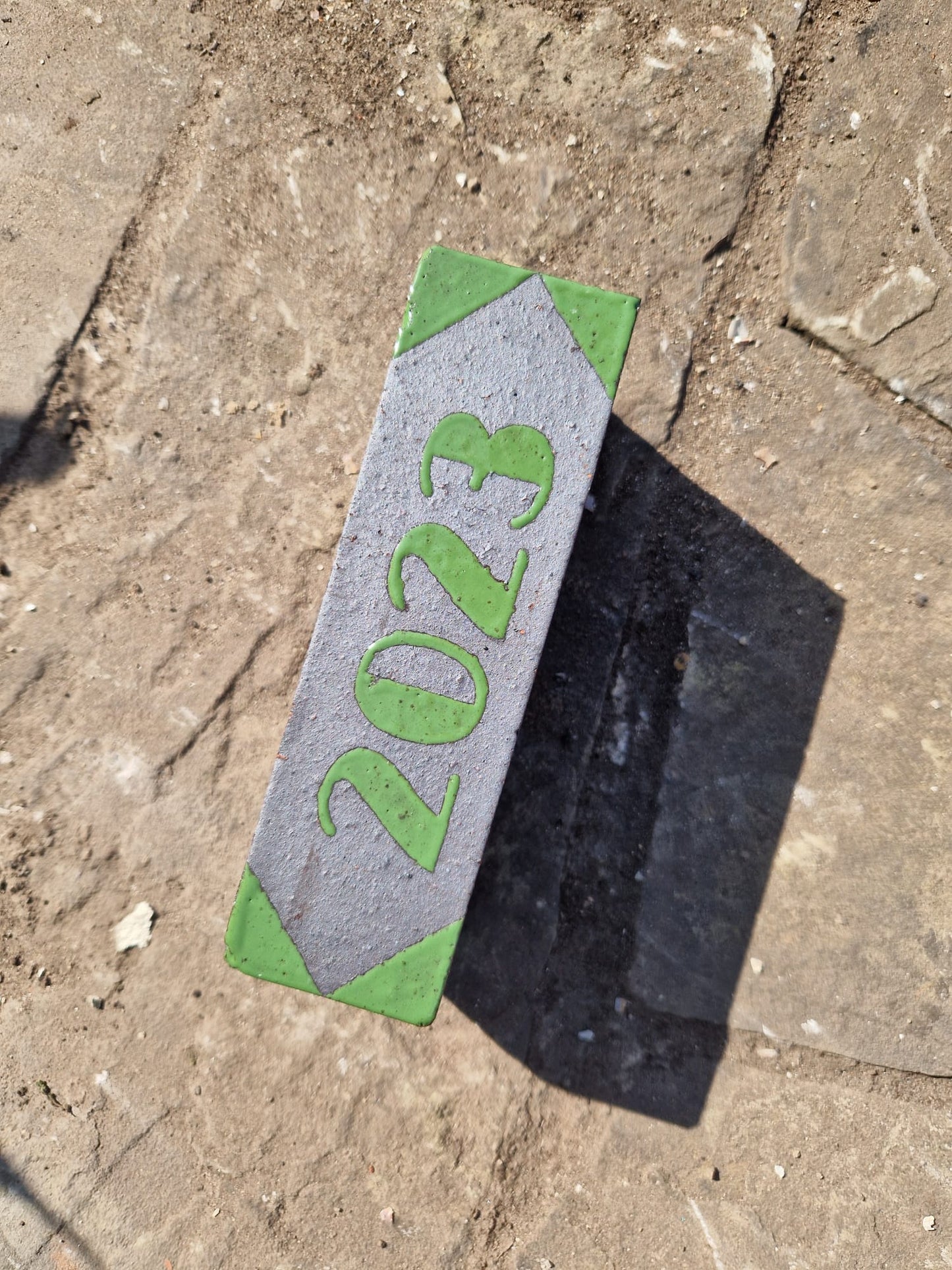 The 2023 marker brick photographed at an angle on stone paving