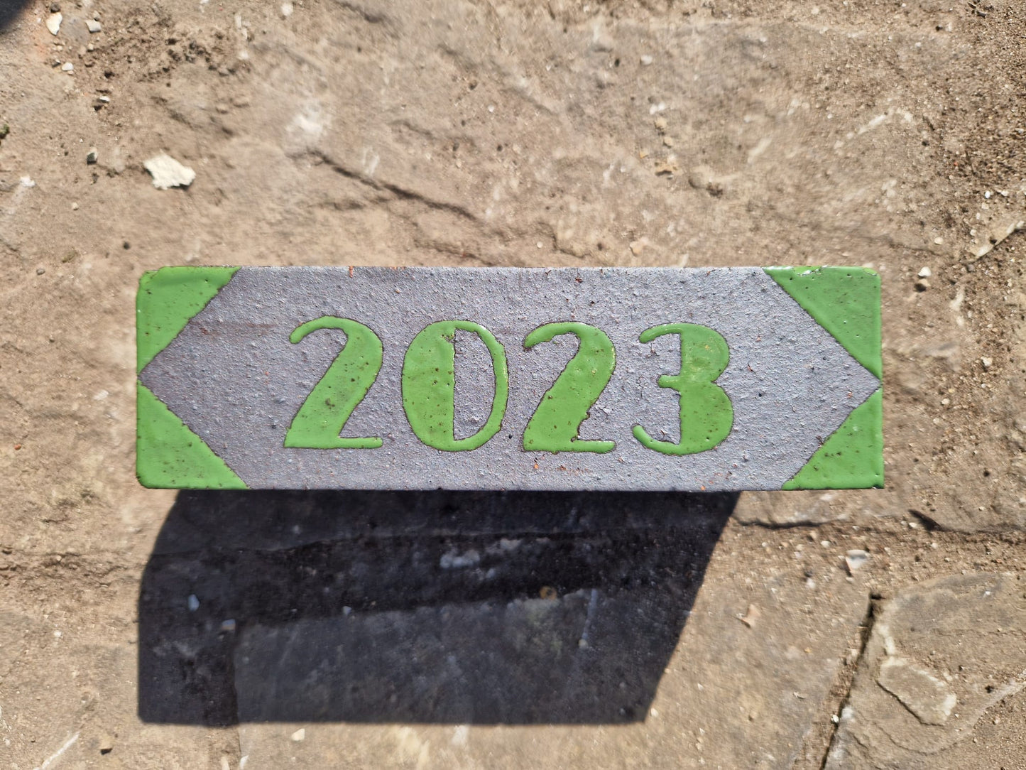Dated marker brick reading 2023, glazed in green with chevron ends