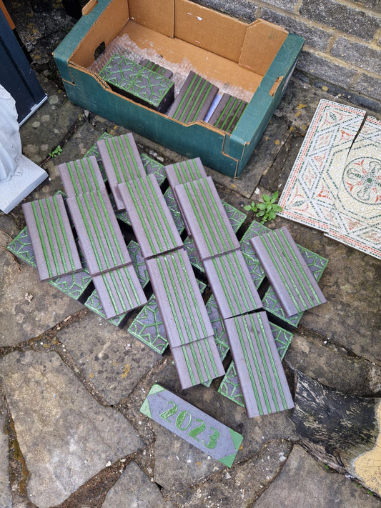 The full set of customized glazed bricks laid out, showing geometric, fluted and dated designs